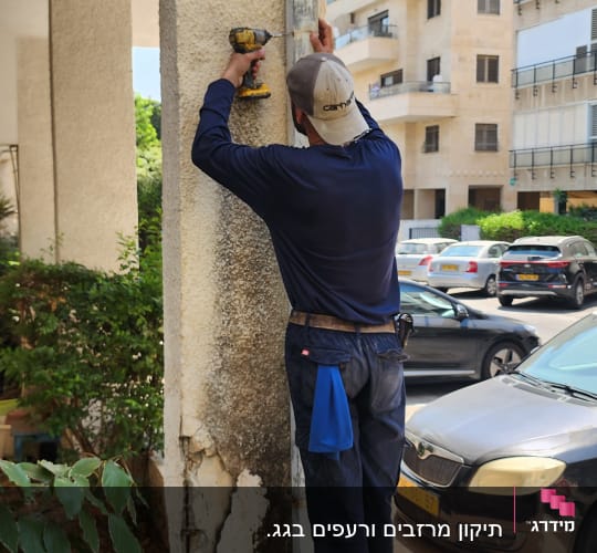 אדם קודח בעמוד מתחת לגג בניין